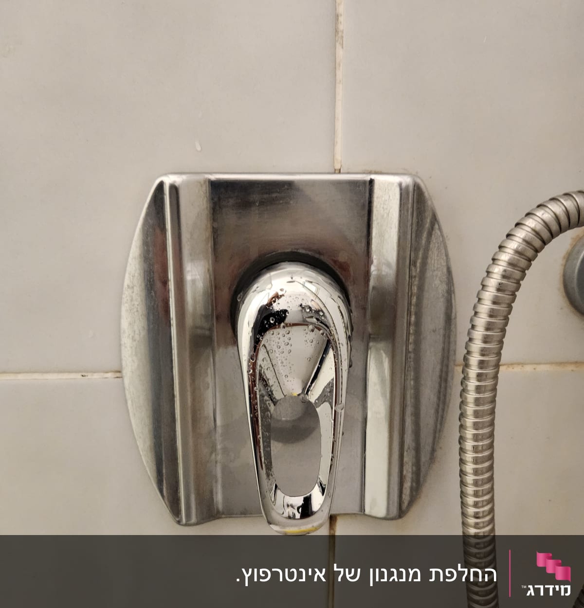 ברז כרום עם צינור מתכת על קיר אריחים
